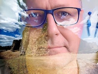 a photo of a man with glasses and a castle in the background